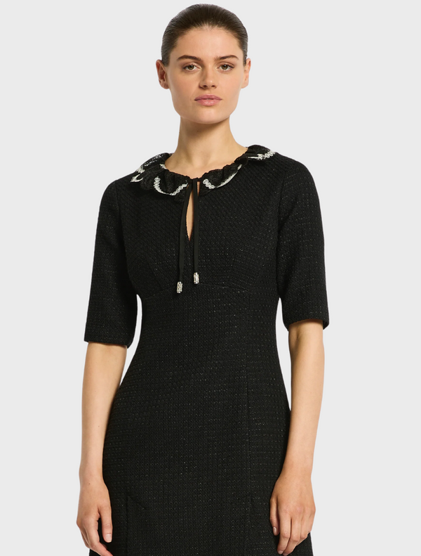 The model showcases a black dress with a daring side slit, highlighting elegance and fashion.