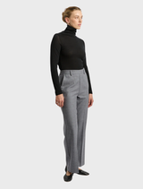 Black merino turtle neck tee draped on a mannequin, illustrating its fitted silhouette and versatile look.
