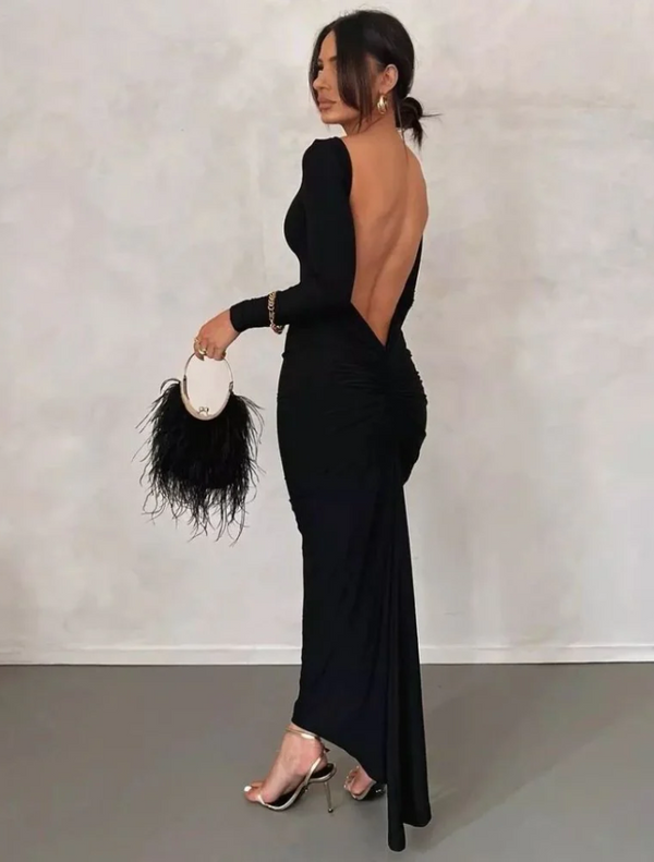 Back view of a woman in a black open-back dress, holding a Penny Feathered Frame Bag in black.