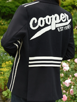Black Cooper Club Jacket draped over a chair, emphasizing its elegant cut and versatile fashion appeal.