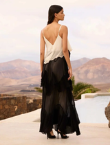 Elegant black and ecru maxi dress featuring ruffles, cutouts, and a removable belt with a tie-dye flower for added style.