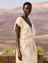 Flowing ecru dress featuring a V-neck, black accents, and adjustable tie, designed for a sophisticated and feminine style.