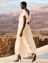 Flowing ecru dress featuring a V-neck, black accents, and adjustable back tie, designed for a sophisticated feminine style.