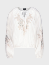 White blouse featuring colorful embroidered flowers on the front, showcasing a delicate and stylish design.