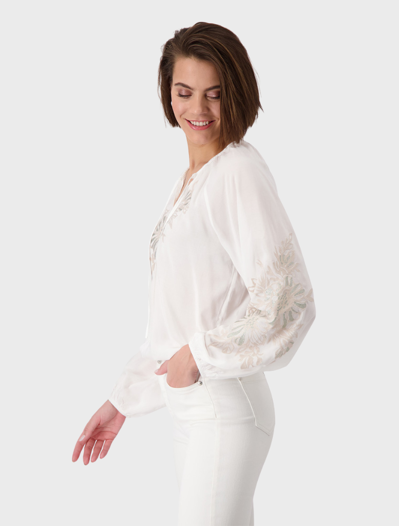 White blouse with intricate floral embroidery, highlighting a blend of simplicity and artistic detail.