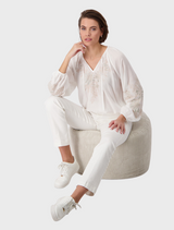 White blouse decorated with colorful flower embroidery, combining elegance with a playful design.