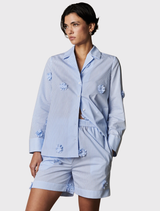 Light blue and white striped blouse with floral appliqués, notched lapel, and wide cuffs for a modern, feminine look.
