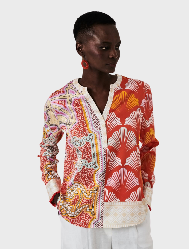 A woman in a tomato multi-colored blouse and pants, showcasing a vibrant and stylish outfit.