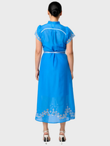Back view of a woman in a blue silk cotton embroidered dress, showcasing the delicate smock yoke design.