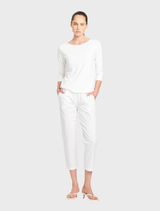 White relaxed boat neck blouse on a flat surface, featuring a minimalist design suitable for casual wear.