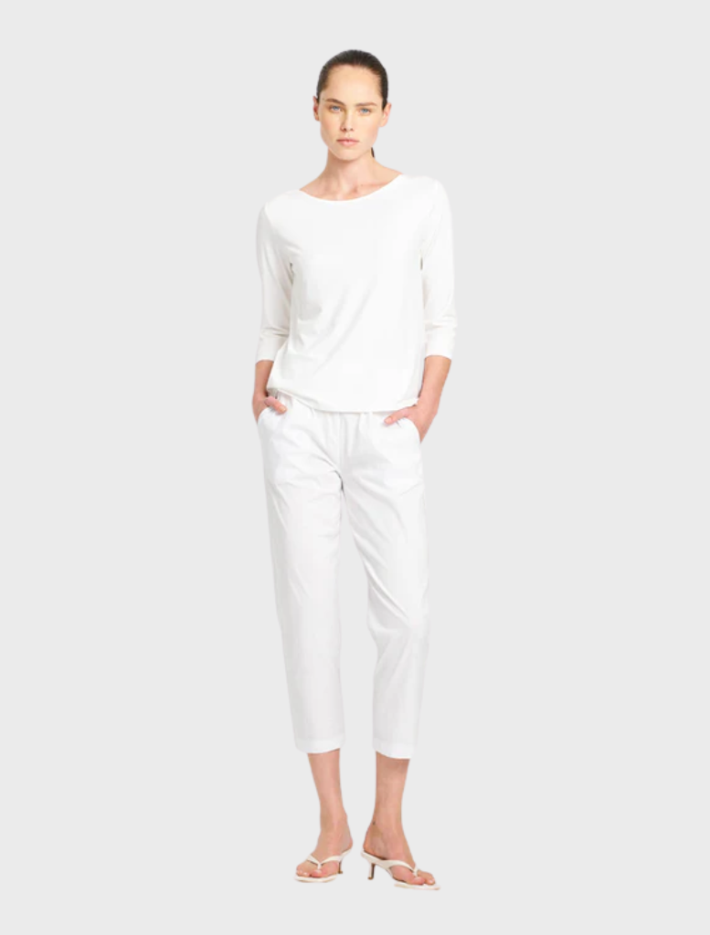 White relaxed boat neck blouse on a flat surface, featuring a minimalist design suitable for casual wear.