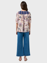 Multi-printed short-sleeve top showcasing a contrast yoke and neck bind, embellished with tucks at the seams and sleeves.