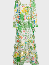  A woman dressed in a floral pattern walks along a path in a park, with lush greenery surrounding her.