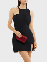 A woman in a black dress holds a burgundy Brooks Hotfix clutch showcasing a stylish and elegant look.