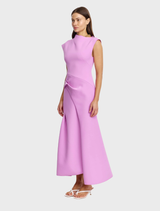The Zinnia Pink Burbank Maxi Dress showcases a modern architectural design with bold color and refined structure.
