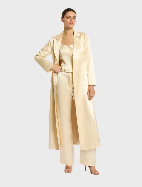 A buttermilk trench coat hanging on a rack, showcasing its elegant design and soft color.