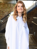 White 'C You Soon' shirt with drop shoulders, blouson sleeves, and front pocket featuring 'Cooper' embroidery for versatile styling.
