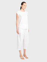 Bright café with white decor, wooden tables, and chairs, creating a serene environment for enjoying coffee and pastries.