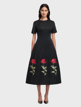 Stunning ebony midi dress with delicate rose details, designed for a chic and elegant look at any gathering.
