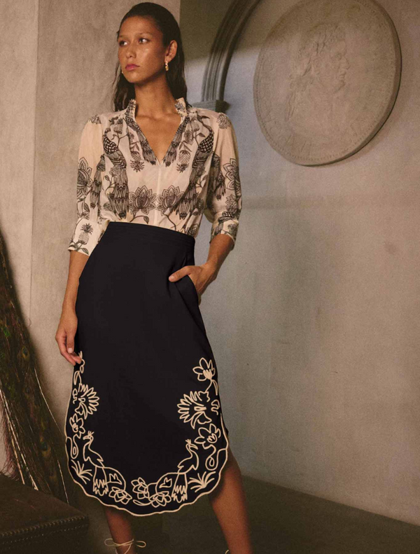 Model showcases a black midi skirt with intricate embroidered details, named Cascadia Embroidered Linen Viscose Midi Skirt.