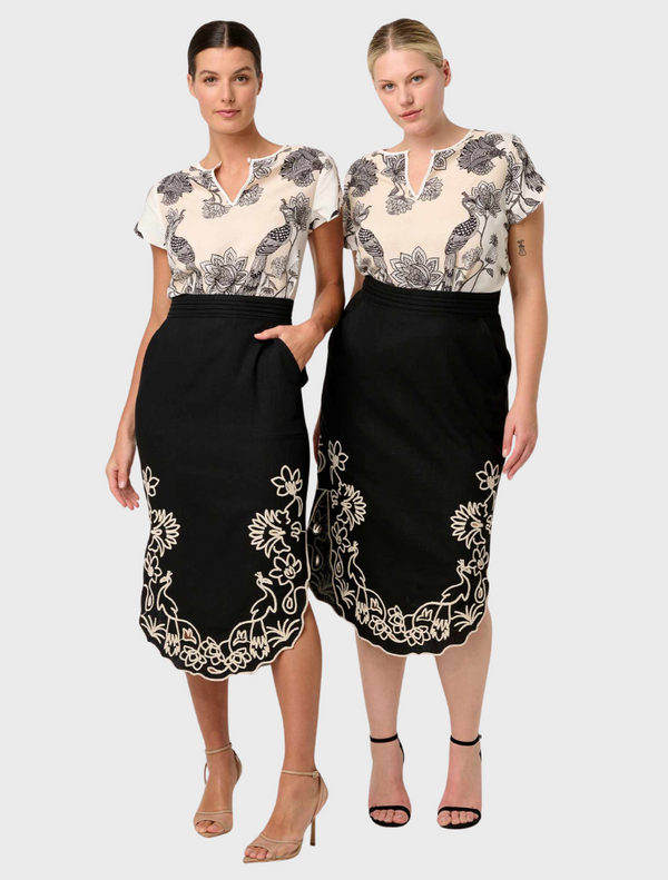 A model displays the Cascadia black midi skirt featuring elegant embroidered designs on a linen-viscose blend fabric.