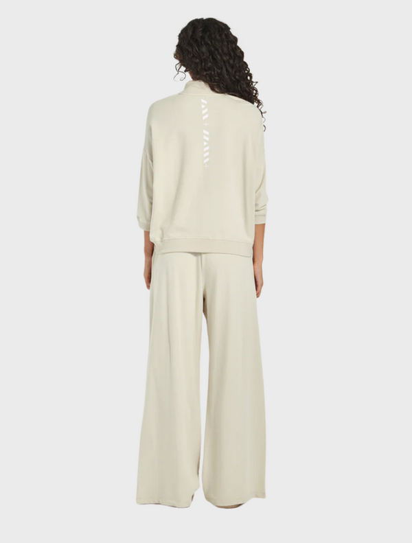  The image features a model dressed in a cream sweatshirt and wide pants, highlighting a relaxed fashion look.