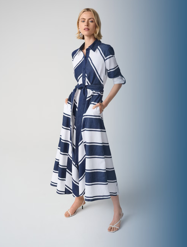 A woman wearing a navy and white striped maxi dress, standing casually outdoors.