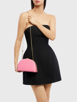 Elegant pink Celeste Curved Clutch showcasing a soft curve, leather-like texture, and options for handheld or shoulder wear.