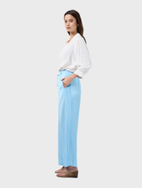Lightweight ice blue pants with tucks, forward side seams, and a waist tie at the folded waistband.