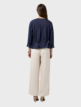 Indigo Chena jacket with tucks, flattering side seams, and a waist tie at the lower edge of the folded waistband.