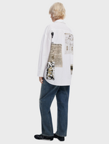 A model showcases a white shirt featuring an abstract design, highlighting contemporary fashion trends.