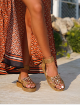 Claire Sandal in bronzo, designed with a fashionable strap and a modern silhouette for versatile wear.