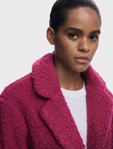 Ice cream pink coat presented on a hanger, illustrating its vibrant color and modern silhouette.