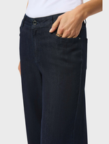 A woman sporting dark blue wide leg jeans, exuding a trendy and comfortable vibe.