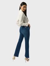 A woman wearing a white shirt and medium blue denim jeans stands confidently, showcasing a classic casual look.