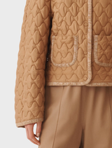 Several light brown coats showcased on hangers, emphasizing their unique styles and textures in a boutique.