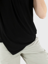Black Stine top presented on a hanger, emphasizing its contemporary cut and fabric quality.