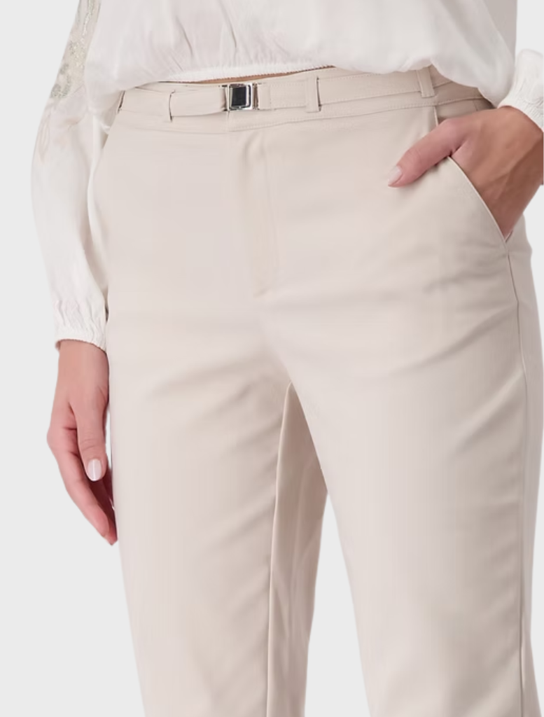 A model wears a crisp white blouse and tailored white pants, embodying a fresh and modern fashion aesthetic.