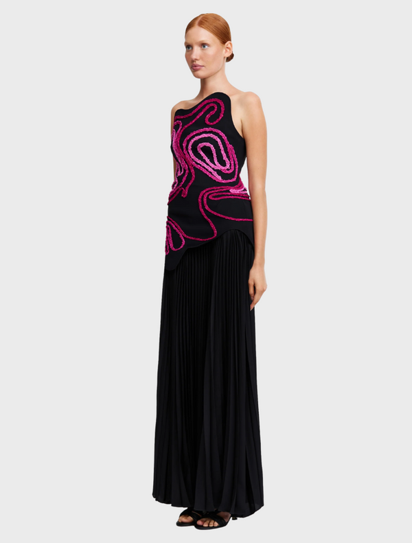 The dress is black with a pink swirl pattern, combining elegance and contemporary design elements.