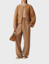 Light brown coats displayed on hangers, showcasing various styles and textures in a retail setting.