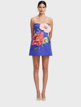  A model showcases a blue dress adorned with a vibrant floral pattern.