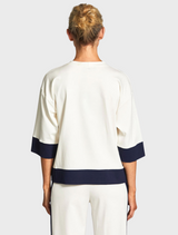 The model showcases a white top and navy pants, creating a sophisticated and trendy appearance.