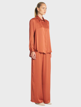 Copper Maxi Pace Pant laid flat, emphasizing its tailored fit and vibrant color against a neutral backdrop.