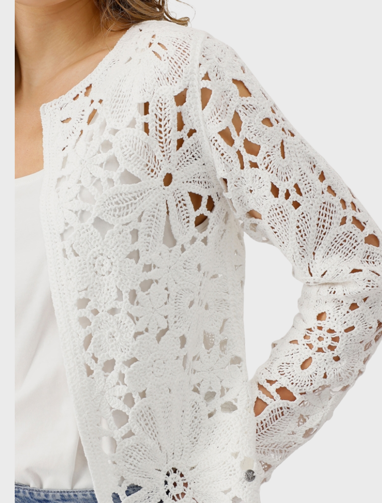 Dressed in a white lace top and blue jeans, a woman poses, highlighting her fashionable attire.
