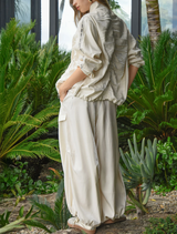 Modern cream pant with a shiny texture, elastic drawstring waist, and voluminous legs for fluid movement and comfort.