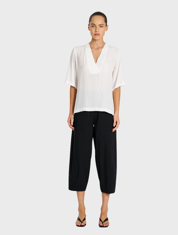 Black cropped Tuscan pants displayed on a white background, showcasing a sleek and modern design.