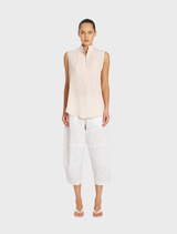 White cropped Tuscan pants displayed on a hanger, showcasing a sleek and modern design suitable for casual or formal wear.