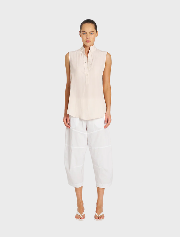 White cropped Tuscan pants displayed on a hanger, showcasing a sleek and modern design suitable for casual or formal wear.