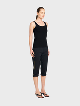 A woman in a black tank top paired with black cropped cargo pants, presenting a sleek and fashionable appearance.