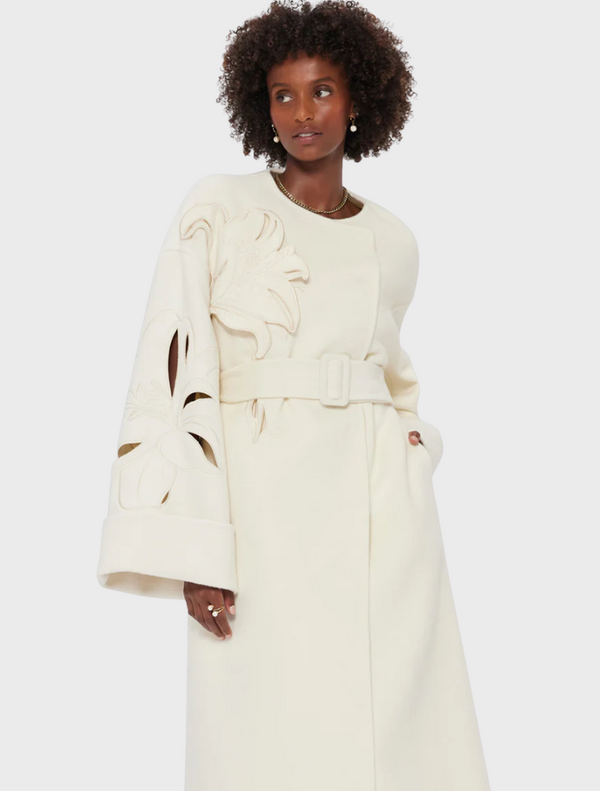 A model showcases a stylish white coat over a matching dress, exuding elegance and sophistication.